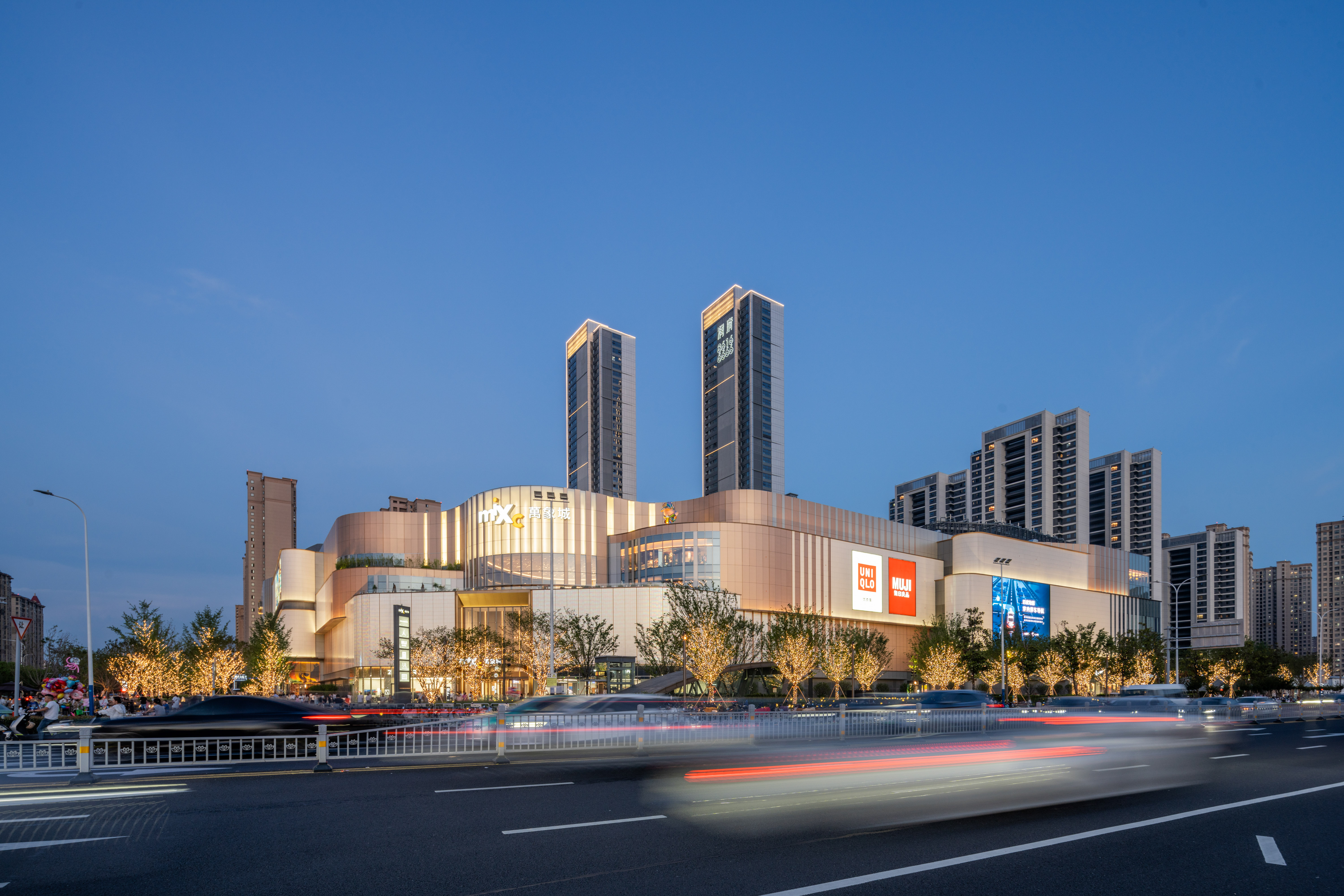 现代购物中心内部多层结构，透明玻璃天窗顶棚和扶梯连接各楼层。