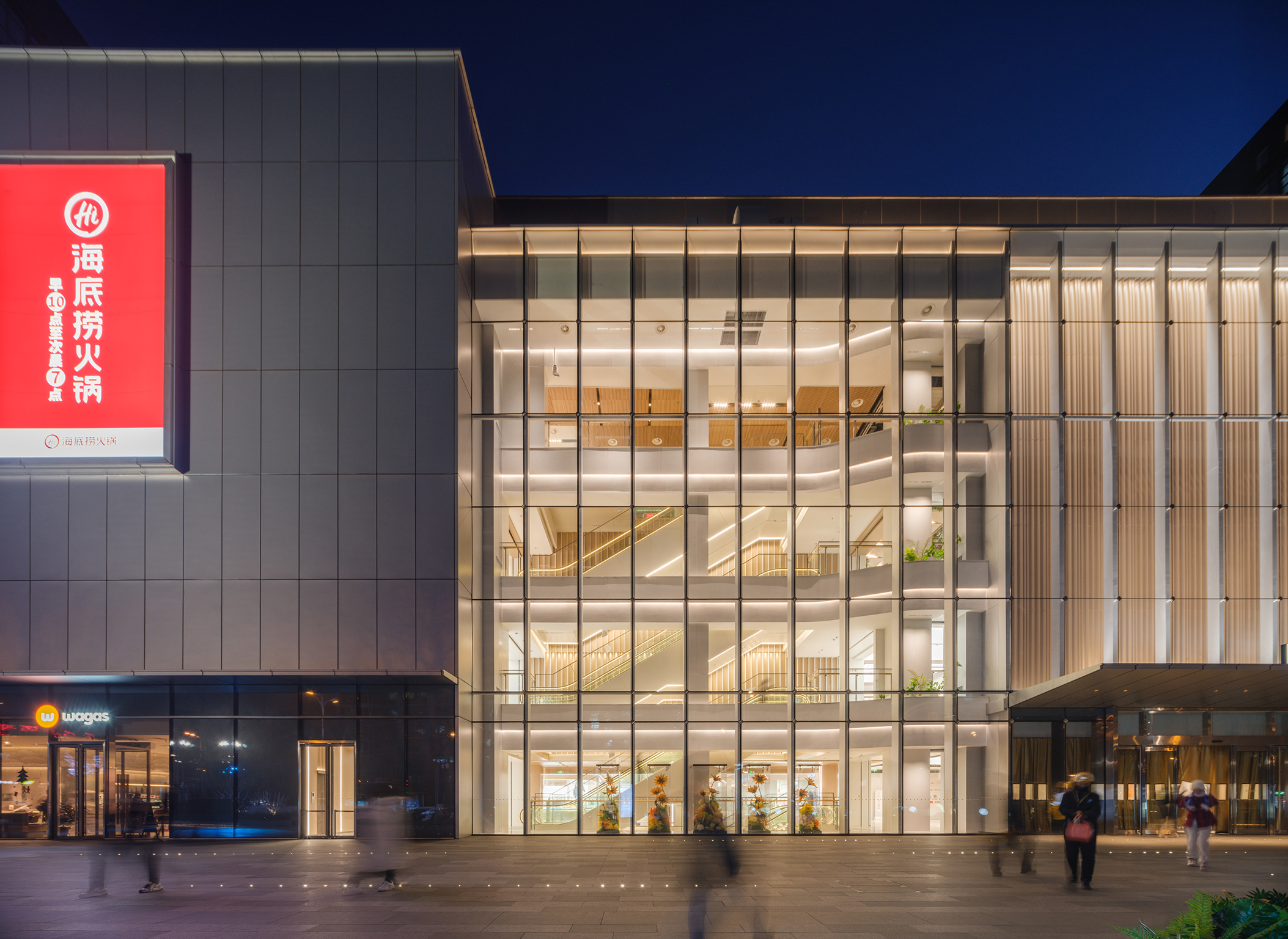 现代购物中心内部多层结构，透明玻璃天窗顶棚和扶梯连接各楼层。