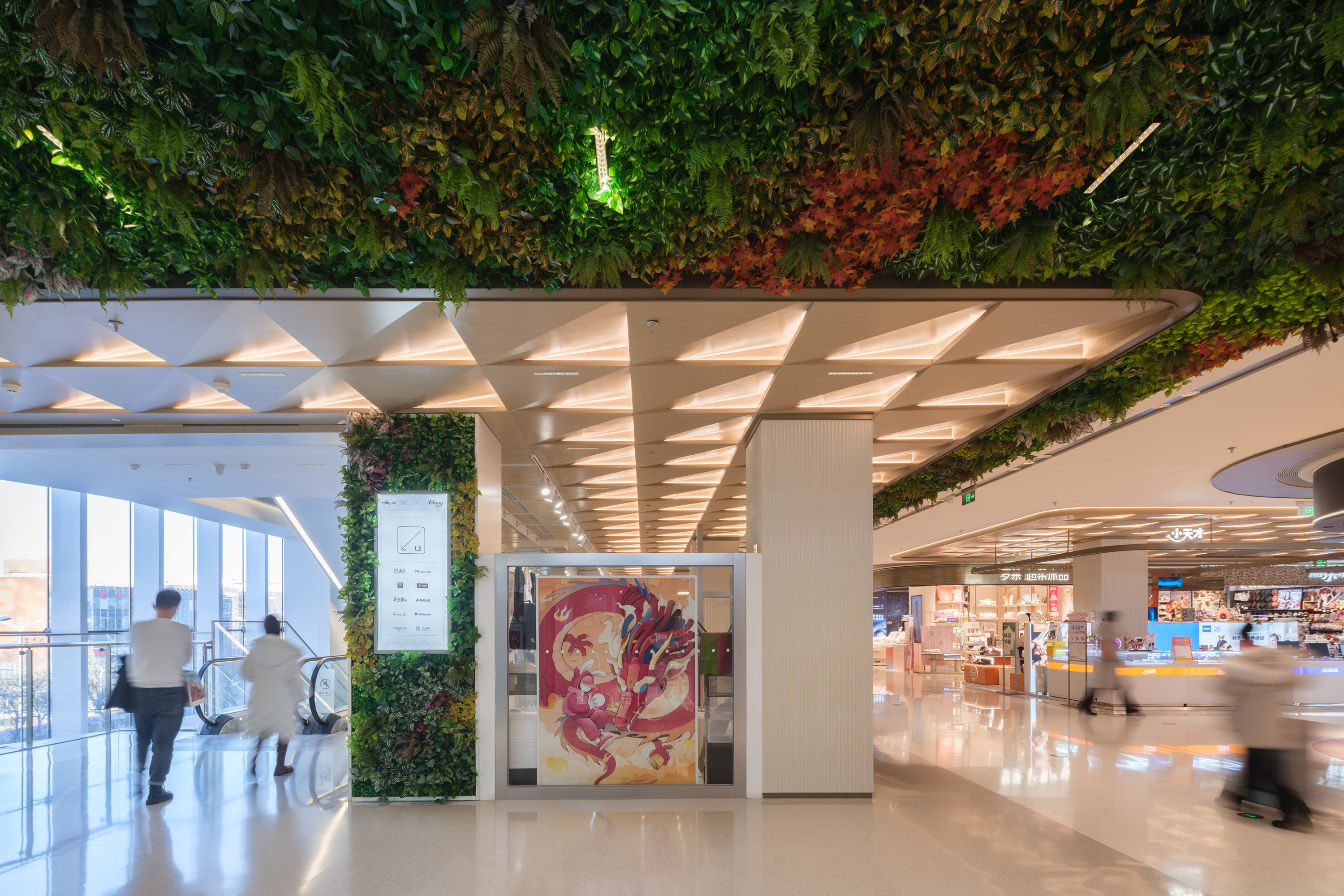 购物中心内现代圆形天花板，中央区域有三角形镜面装饰，周围环绕暖色灯光。