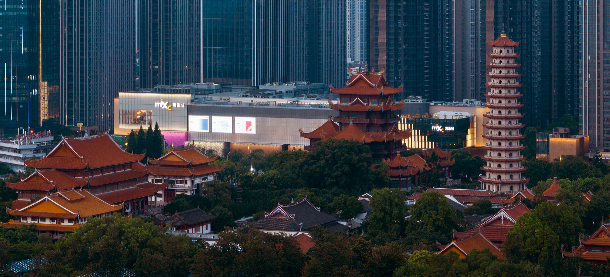 现代购物中心内部多层结构，透明玻璃天窗顶棚和扶梯连接各楼层。