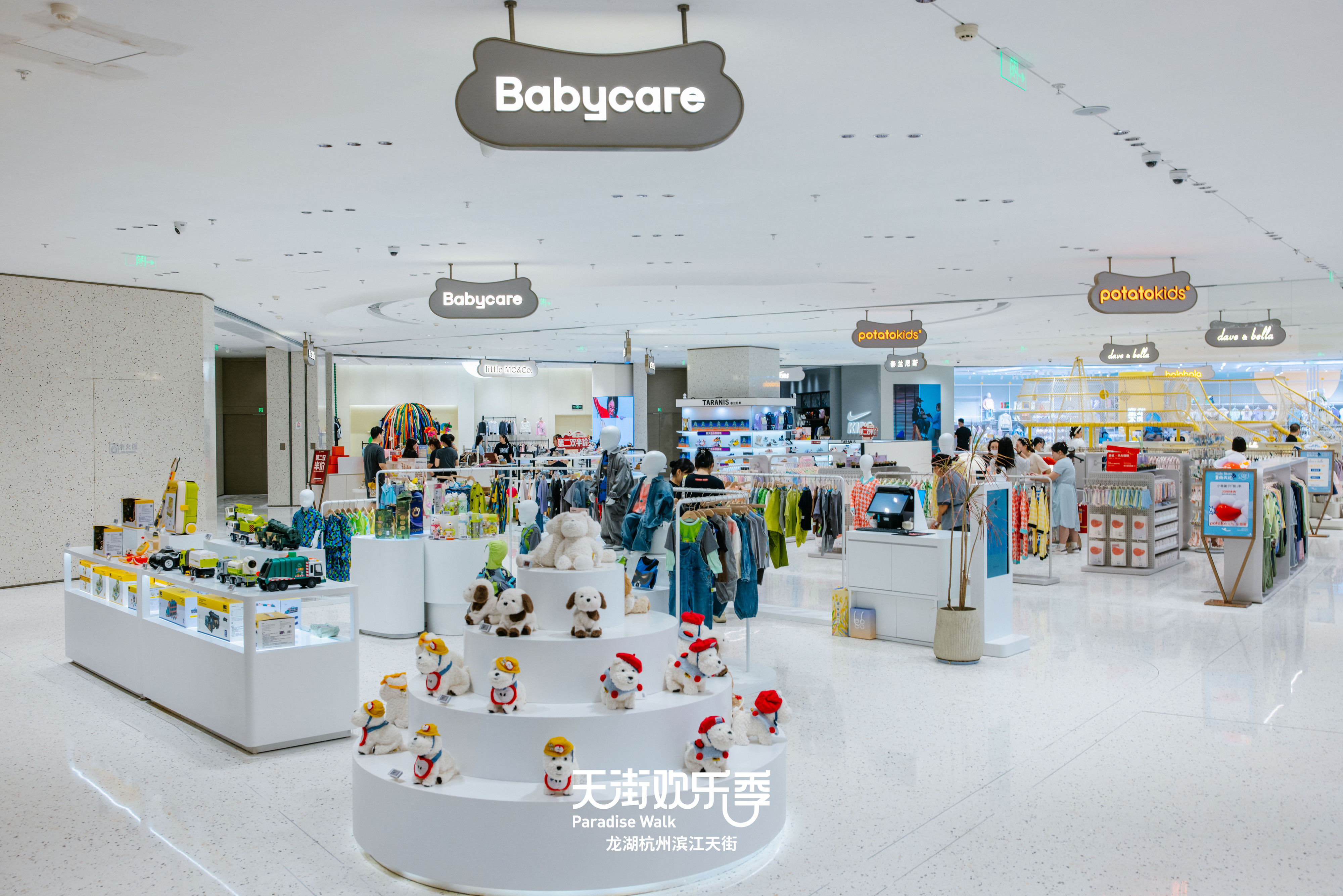 现代购物中心内部，中央有大型玻璃穹顶和多层环绕商铺，右侧有自动扶梯。