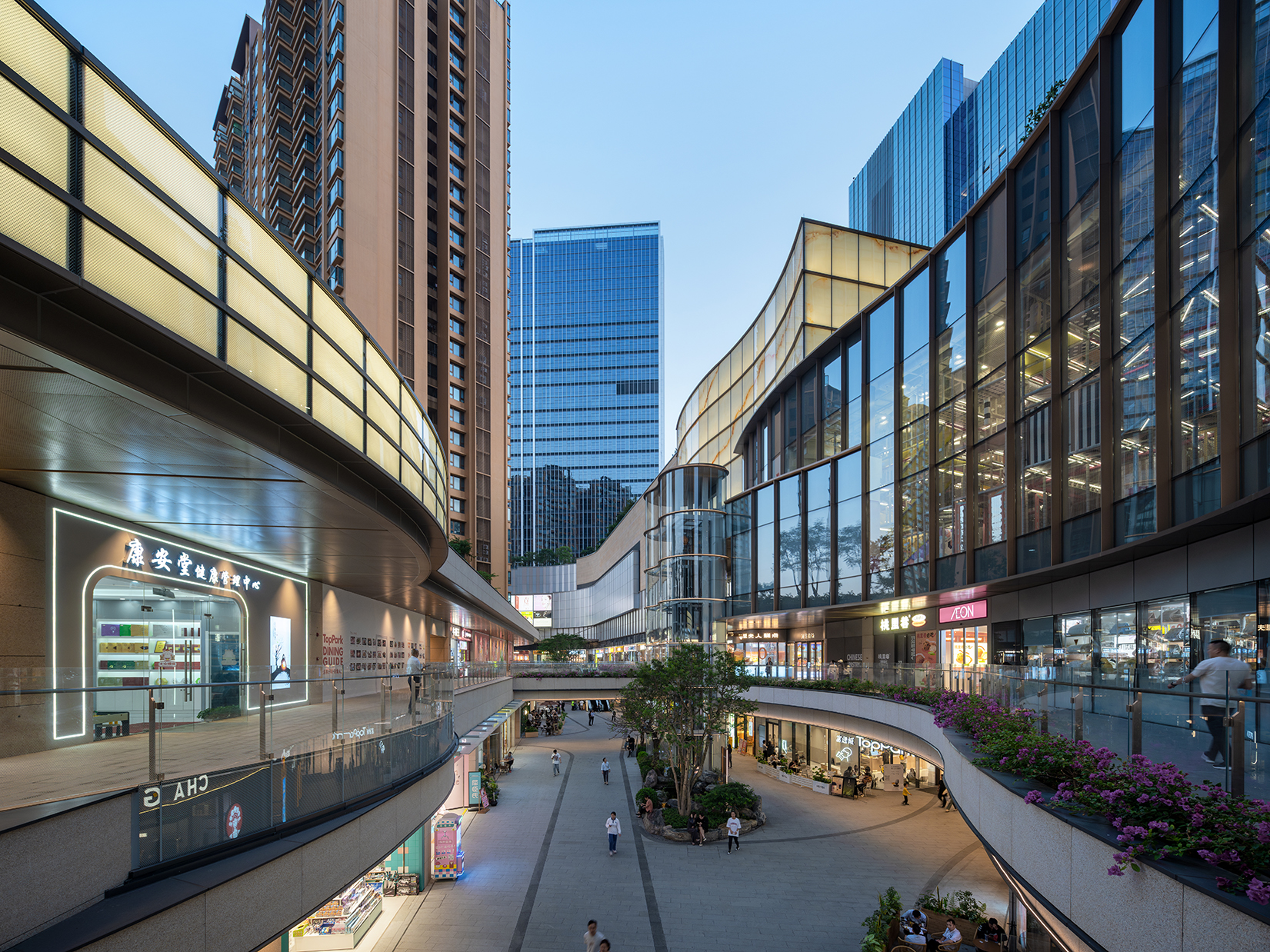 购物中心内现代圆形天花板，中央区域有三角形镜面装饰，周围环绕暖色灯光。